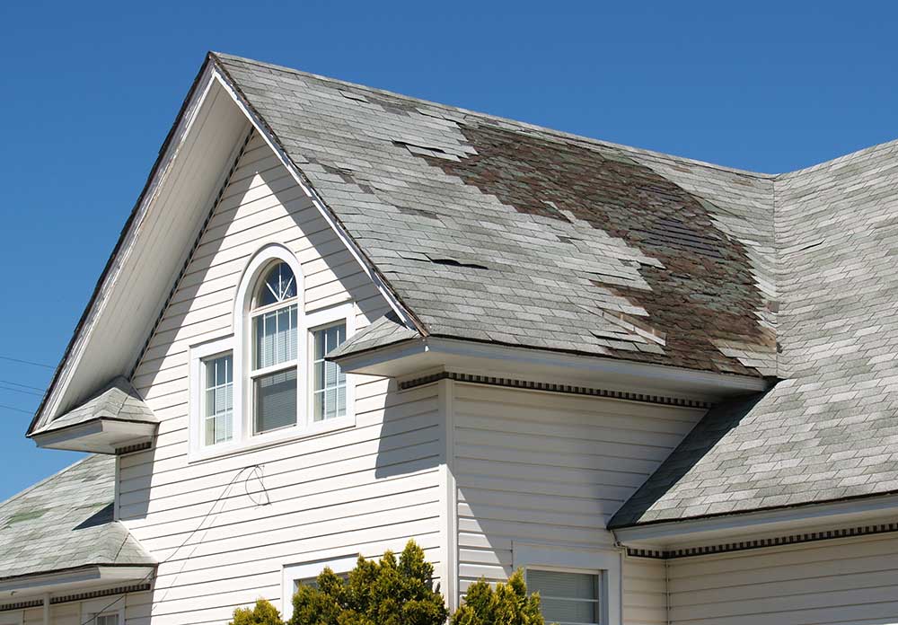 Damaged shingles on a residential roof that need to be examined and repaired by roof specialists